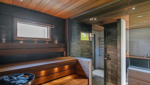 A modern bathroom with wooden flooring, a glass shower enclosure, and a built-in bench.