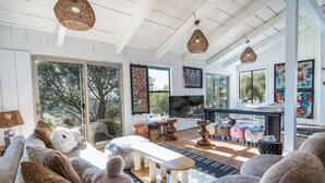 Un salón amplio con un televisor grande, asientos cómodos y vistas al exterior.