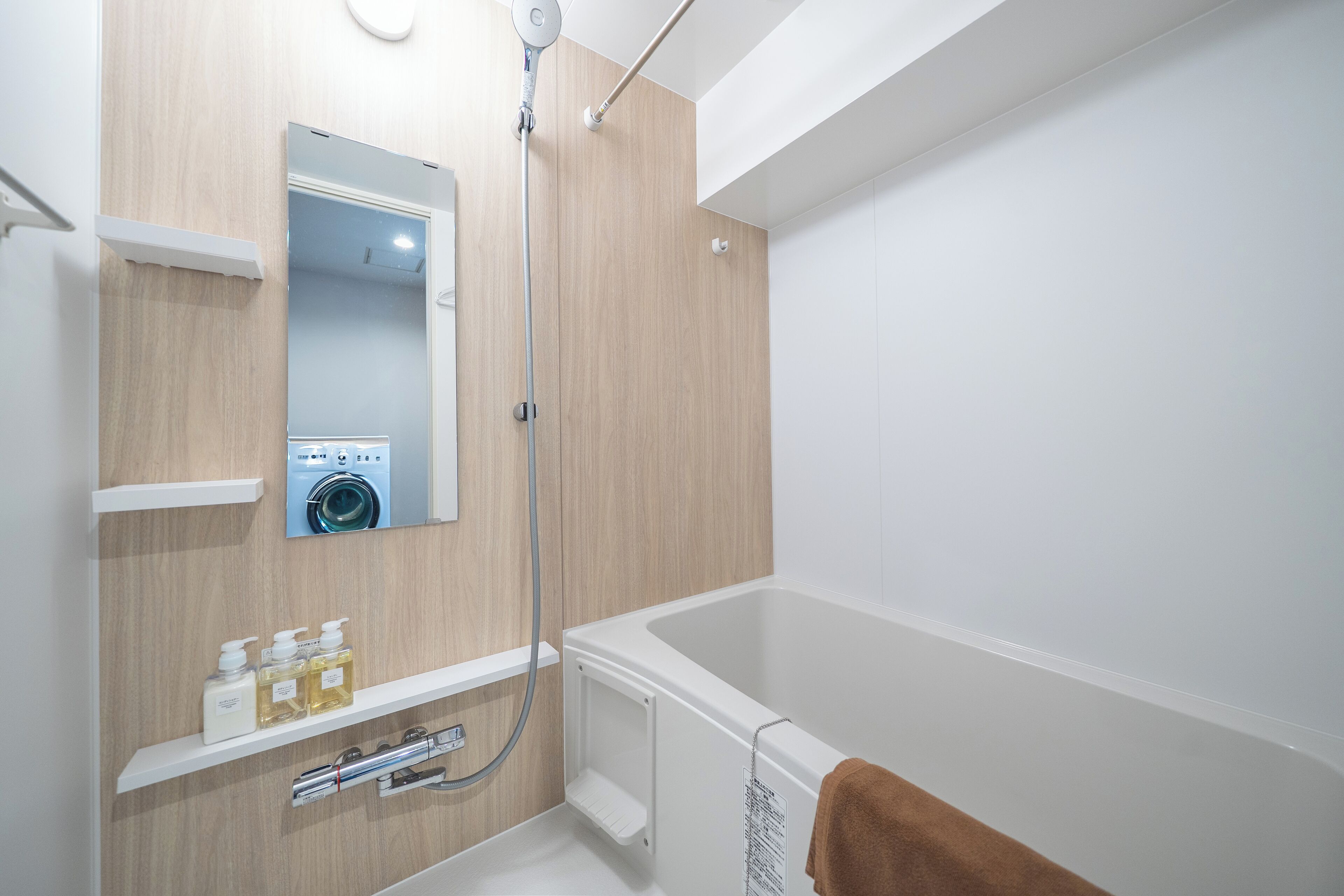 Un baño moderno con lavadora incorporada, bañera y ducha.