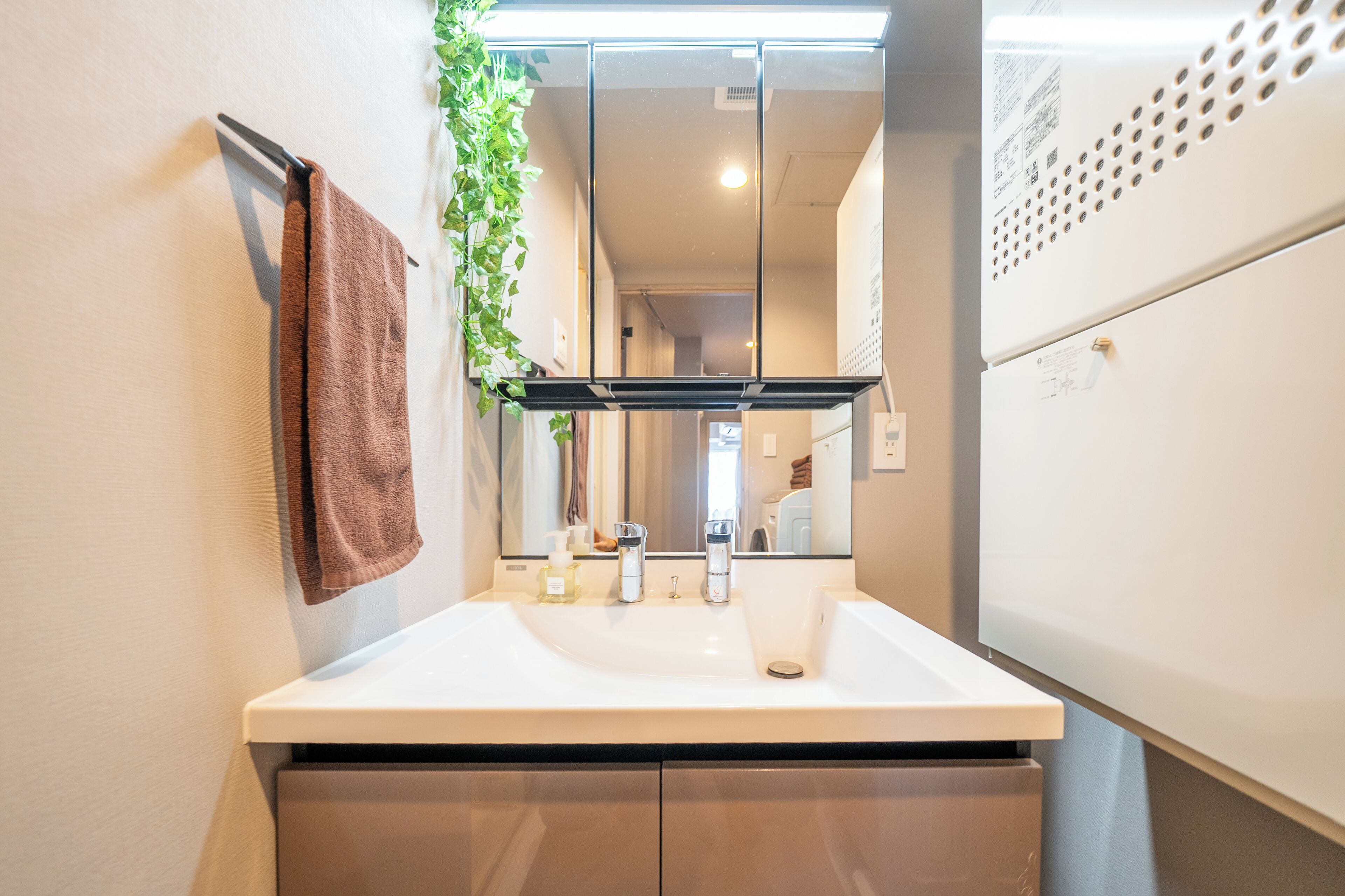 A bathroom with a white sink, a mirror, and a towel hanging on the wall.