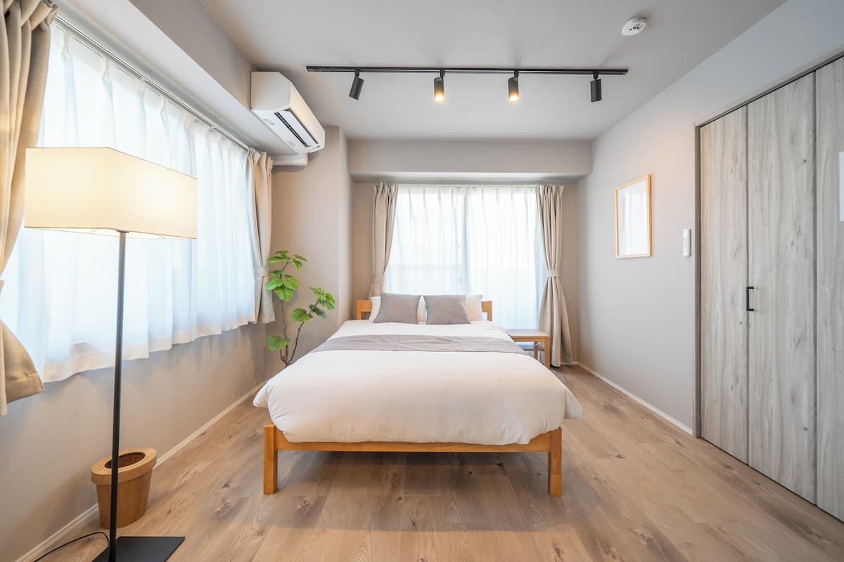 Une chambre à coucher avec un lit en bois, une table de chevet, une lampe, une plante en pot et une armoire.
