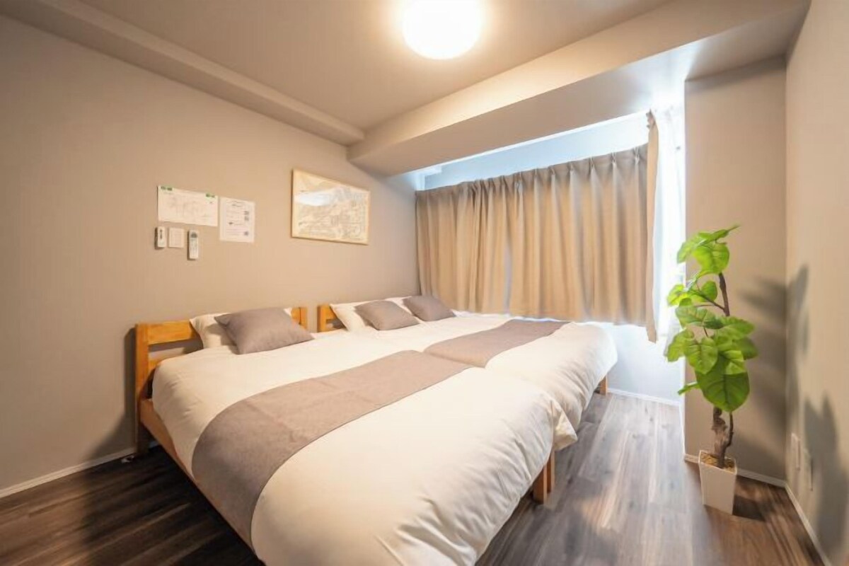 A hotel room with a large bed, a potted plant, and a window with curtains.