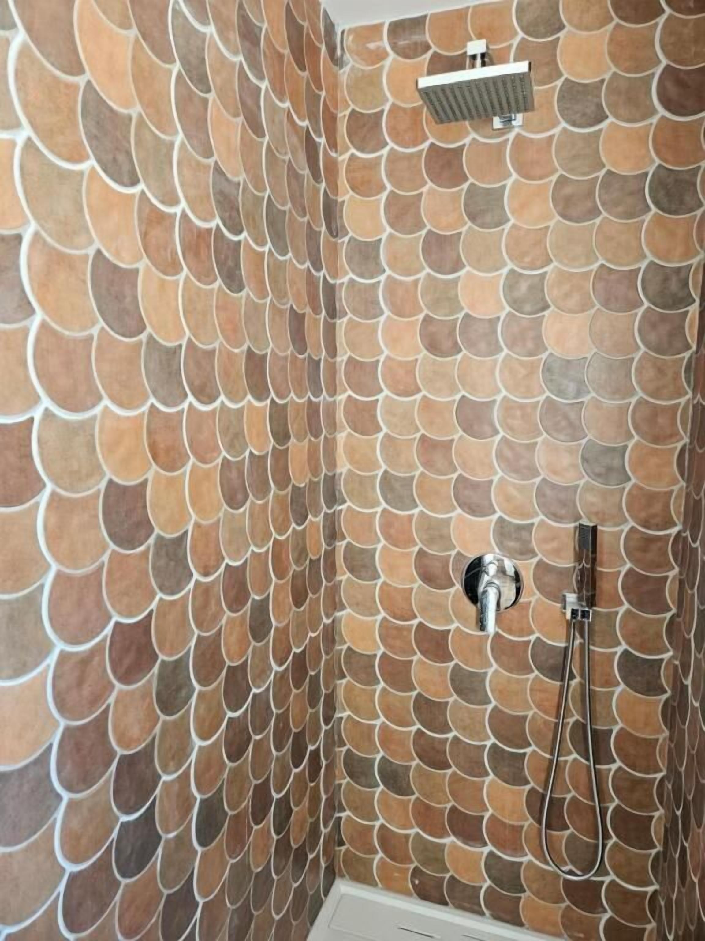 Casa de banho com parede revestida de azulejos com padrão semelhante a escamas.