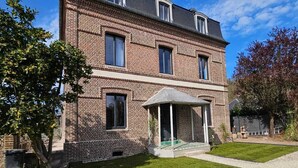 Une maison à deux étages, construite en briques, avec un porche et une allée gravillonnée.
