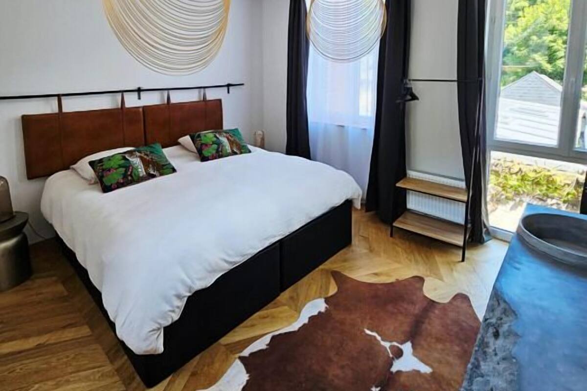 Un dormitorio moderno con una cama grande, suelo de madera y una alfombra de cuero de vaca.
