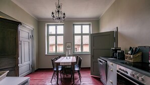 Eine Küche mit Esstisch, Stühlen, einer Kandelaber und einem großen Fenster.