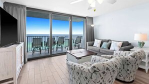 A balcony with a view of the ocean, a sofa set, a coffee table, and a TV. - One Seagrove Place 1404 (Santa Rosa Beach)