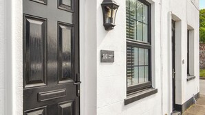 A white building with a black door and window, a sign reading "14 Seagull's Nest," and a black lantern on the wall. - You will just love the open plan ground floor of this historic cottage. (Flamborough)
