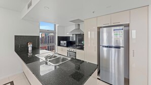 A modern kitchen with a stainless steel refrigerator, a microwave, and a stove. - CLLIX Brisbane Central Apartments (Brisbane)