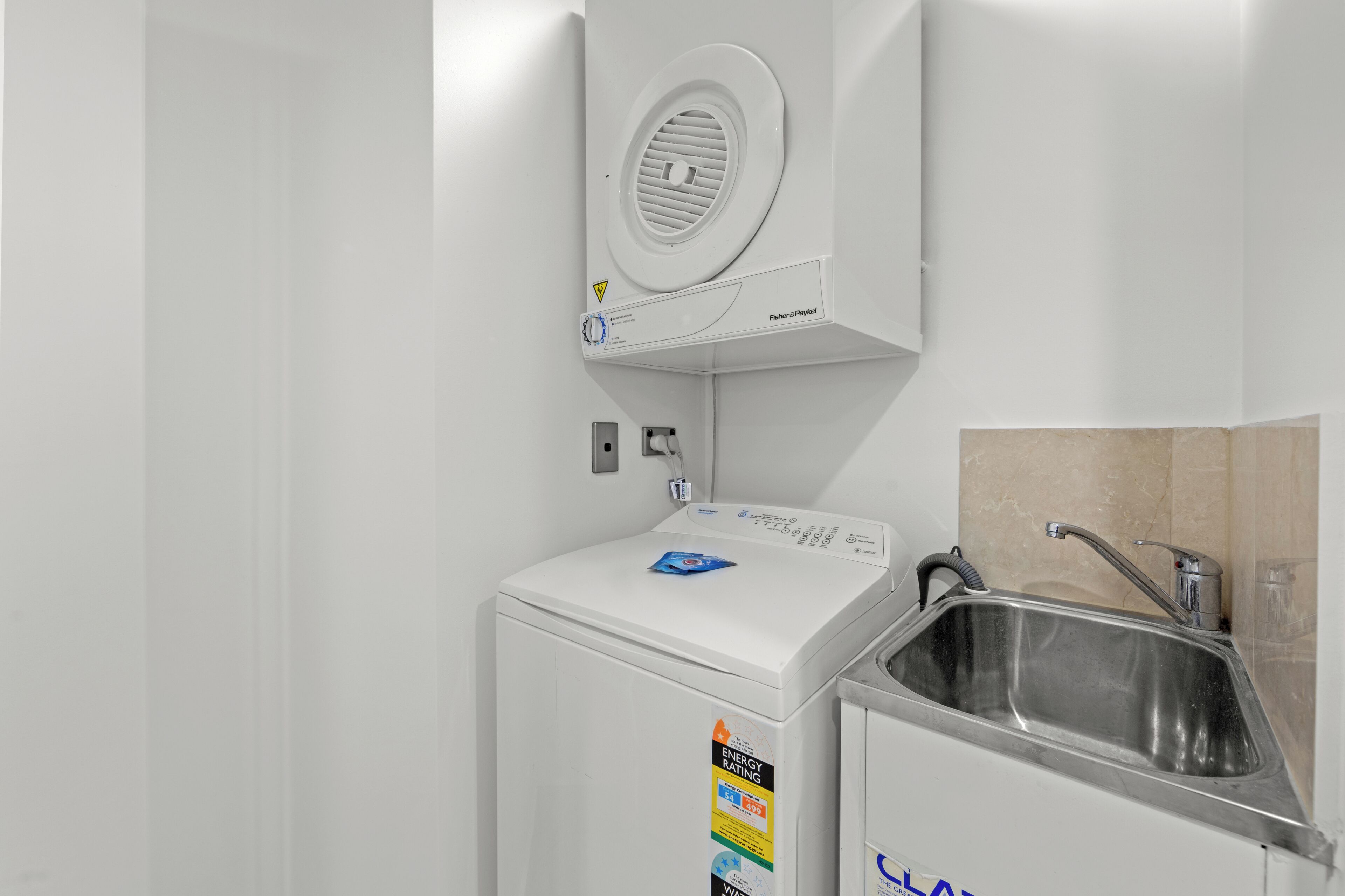 A compact, white laundry machine with a control panel and a water inlet.