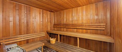 Una sauna con bancos de madera y un asiento con un balde.