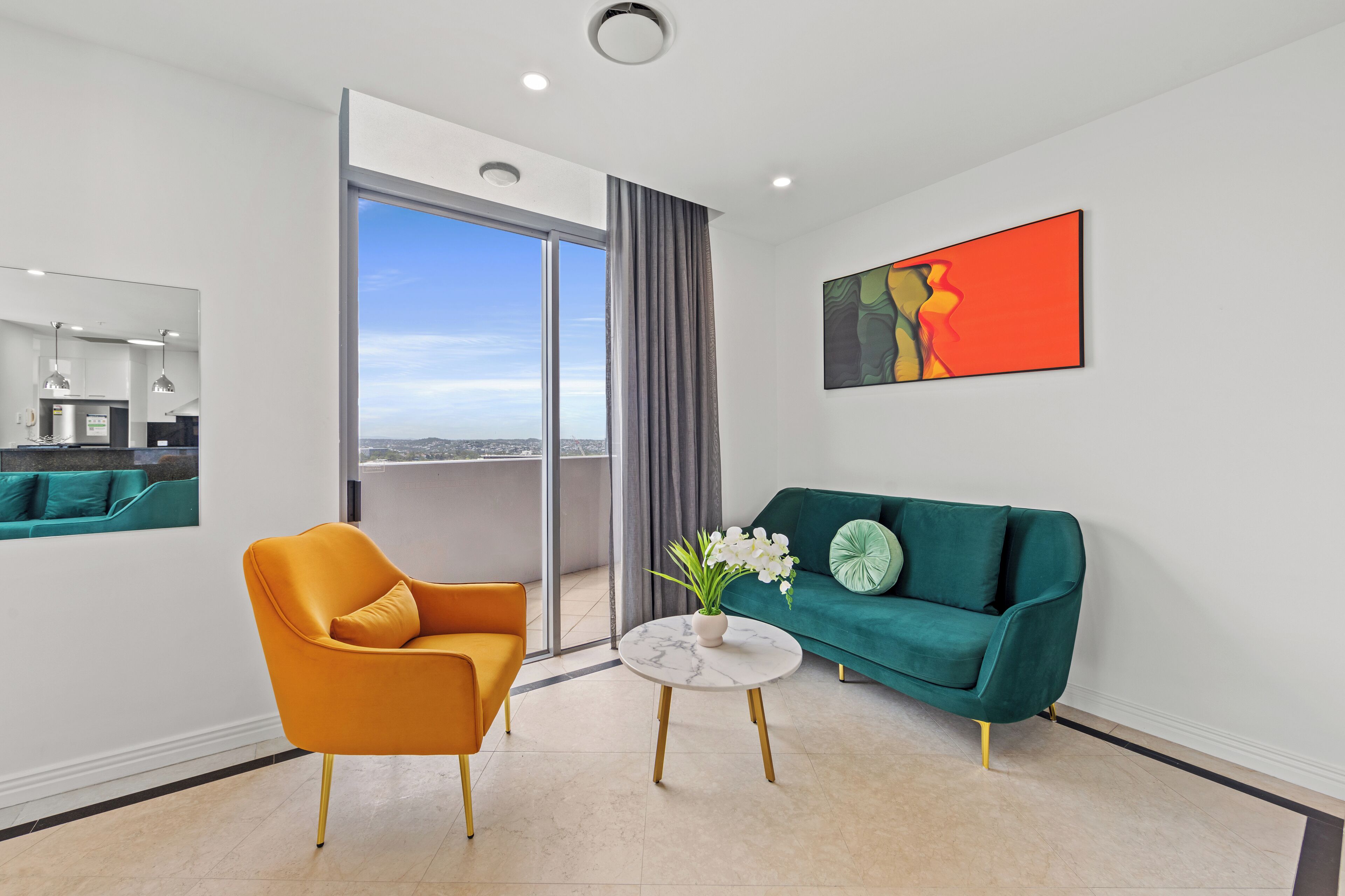 Una sala moderna con un sofá verde, un sillón naranja y una mesa de centro de mármol.
