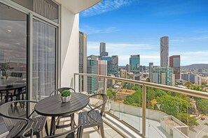 A balcony with a table and chairs, overlooking a cityscape with modern buildings. - CLLIX Brisbane Central Apartments (Brisbane)