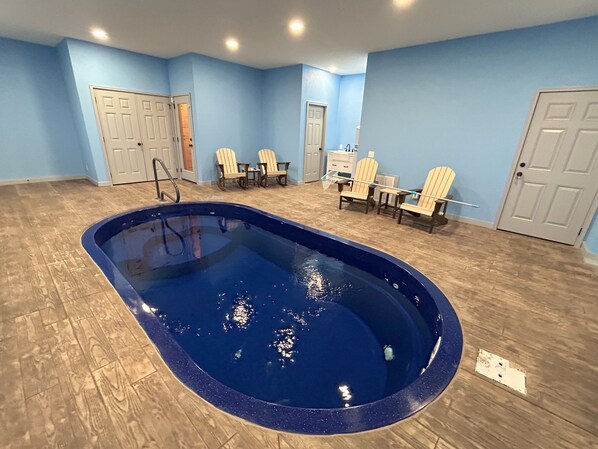 Une piscine dotée d’une terrasse en bois, de murs bleu clair et d’une porte sur l’un des côtés.