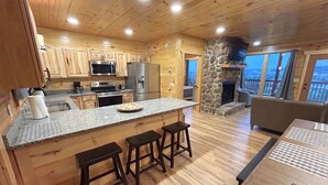 A spacious kitchen with wooden cabinets, a granite countertop, and a stone fireplace.