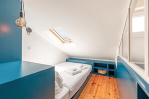 Une chambre à coucher compacte et moderne, avec un lit simple, une petite fenêtre et un puits de lumière.