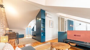 Een moderne woonkamer met een loft-plafond, een eethoek en een keuken met blauwe kastjes.