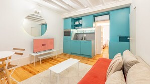 A compact living space with a kitchenette, a television, a dining area with a table and chairs, and a sofa. - GuestReady - Esperança do Cardal R/C (Lisbon)