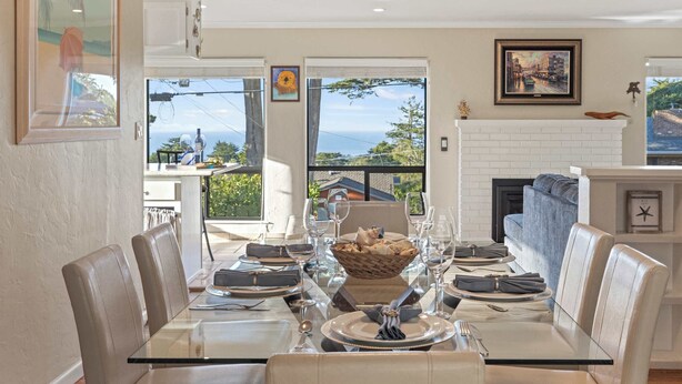Un coin repas avec une table en verre, des fauteuils en cuir et une cheminée.