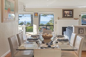 A dining area with a glass table, leather chairs, and a fireplace.