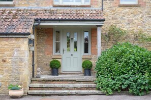Une maison en pierre avec un toit en tuiles, une porte d’entrée et un petit porche avec des marches.