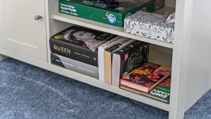 A bookshelf with various items including books, a puzzle box, and a remote control. - Flat with free parking in Oxford (Oxford)