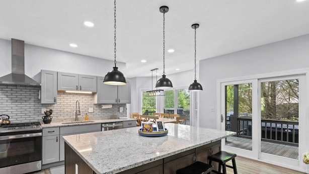 Una cocina moderna con encimeras de granito, electrodomésticos de acero inoxidable e iluminación colgante.