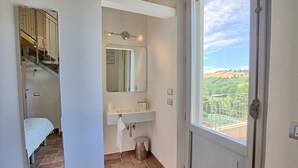 Un baño con lavamanos, espejo y vistas a un balcón.