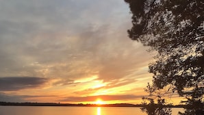 A sunset over a calm lake with a bench in the foreground.