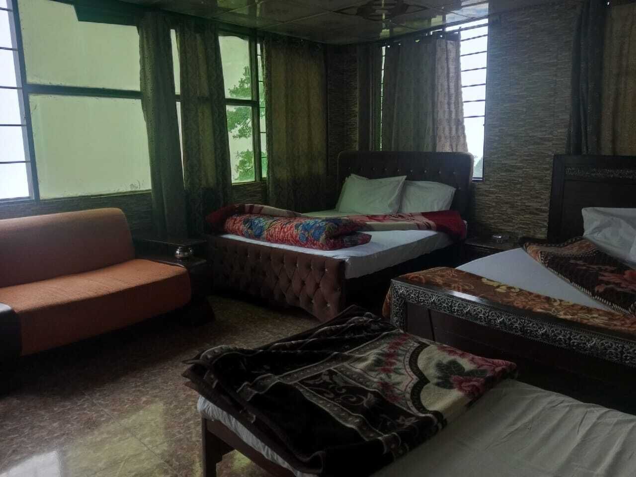 A hotel room with two beds, a sofa, and a large window.