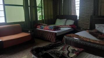 Una habitación de hotel con dos camas, un sofá y un ventanal grande.