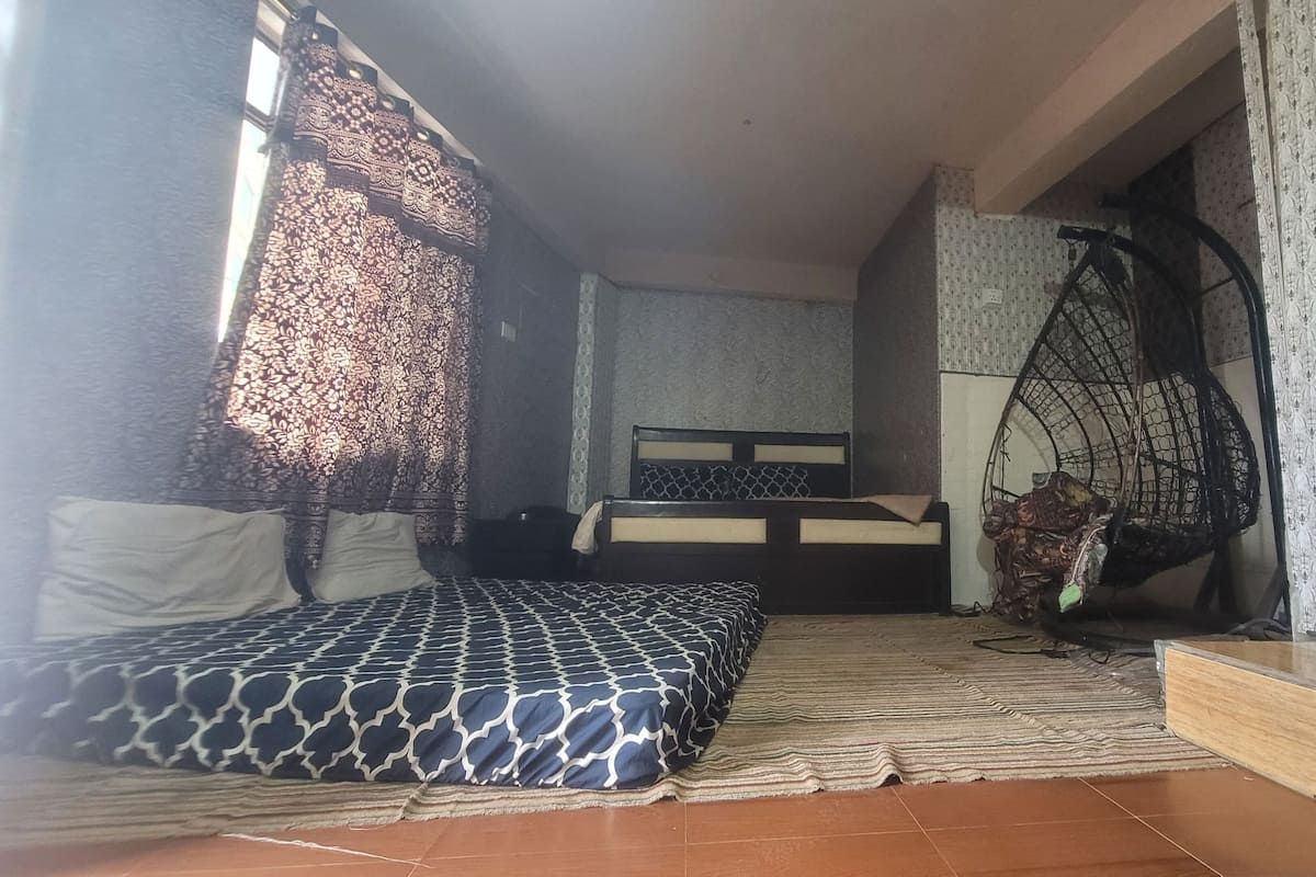 A compact room with a bed, a hanging chair, and a small table.