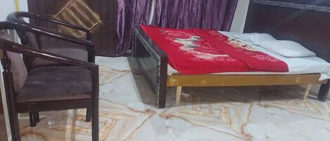 A room with a bed, a chair, a wooden door, and a curtain.