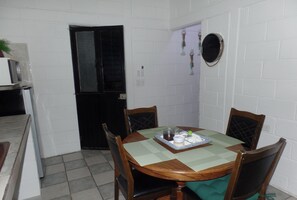 A dining area with a round table, four chairs, a green tablecloth, and a small decorative item on the table.