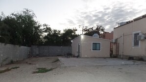 A building with a small patio area, a door, and a window with a metal grille. - 🤑😎❤️ SE FACTURA❤️😎🤑 ARE YOU TRAVELING ON BUSINESS?? (San José del Cabo)
