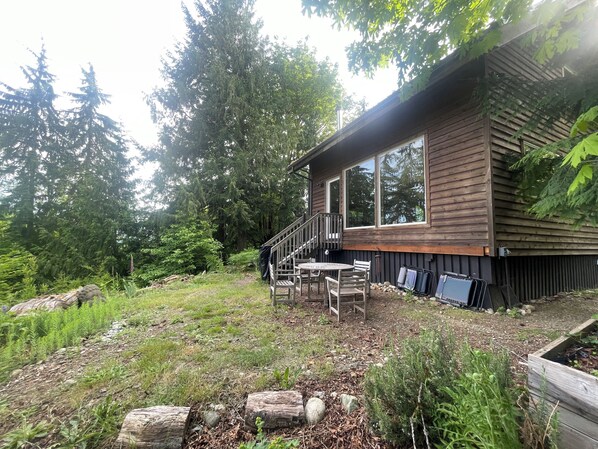 A wooden cabin with a deck, surrounded by dense forest. - Beautiful, peaceful mountain view cabin. (Arlington)