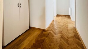 A hallway with wooden flooring and white walls.