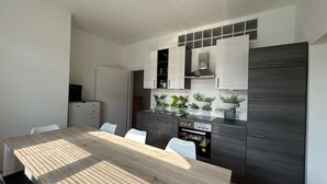 A modern kitchen with dark cabinetry, a wooden dining table, and a built-in oven.