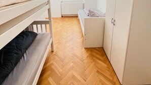 Una habitación con literas, un armario, un radiador y una ventana con persianas.