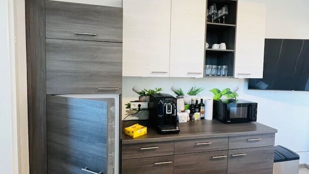 Una cocina moderna con armarios de madera oscura, microondas integrado y cafetera sobre la encimera.