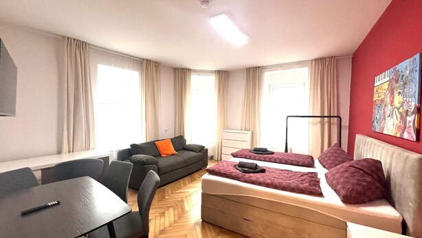 A compact hotel room with a sofa, two single beds, a dining table, and a chair. - Apartment Graz Eggenberg Top 8 (Graz)