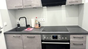 A modern kitchen with grey cabinets, a black stove, and a built-in oven. - Apartment Graz Eggenberg Top 8 (Graz)