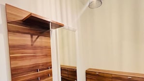 Ein modernes Schlafzimmer mit einem großen Spiegel, einem Holzschrank und einer Pendelleuchte.