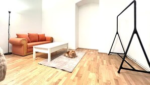 Ein Zimmer mit Holzboden, einem weißen Couchtisch, einer Couch und einem schwarzen Stativ.