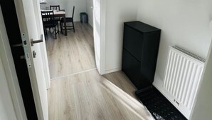 A narrow hallway with a dining area in the background, a black cabinet, and a white radiator. - Living Villa Rebuli! Top 5 (Leitendorf)