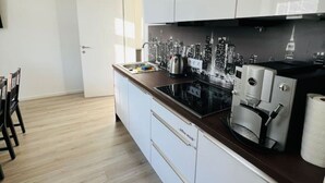 A modern kitchen with white cabinets, a black countertop, and a coffee machine. - Living Villa Rebuli! Top 5 (Leitendorf)