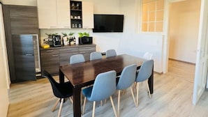 Une cuisine moderne avec un coin repas, un plancher en bois et un téléviseur à écran plat.