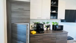 Une cuisine moderne avec des meubles de couleur bois foncé, un four à micro-ondes encastré et une machine à café posée sur le plan de travail.