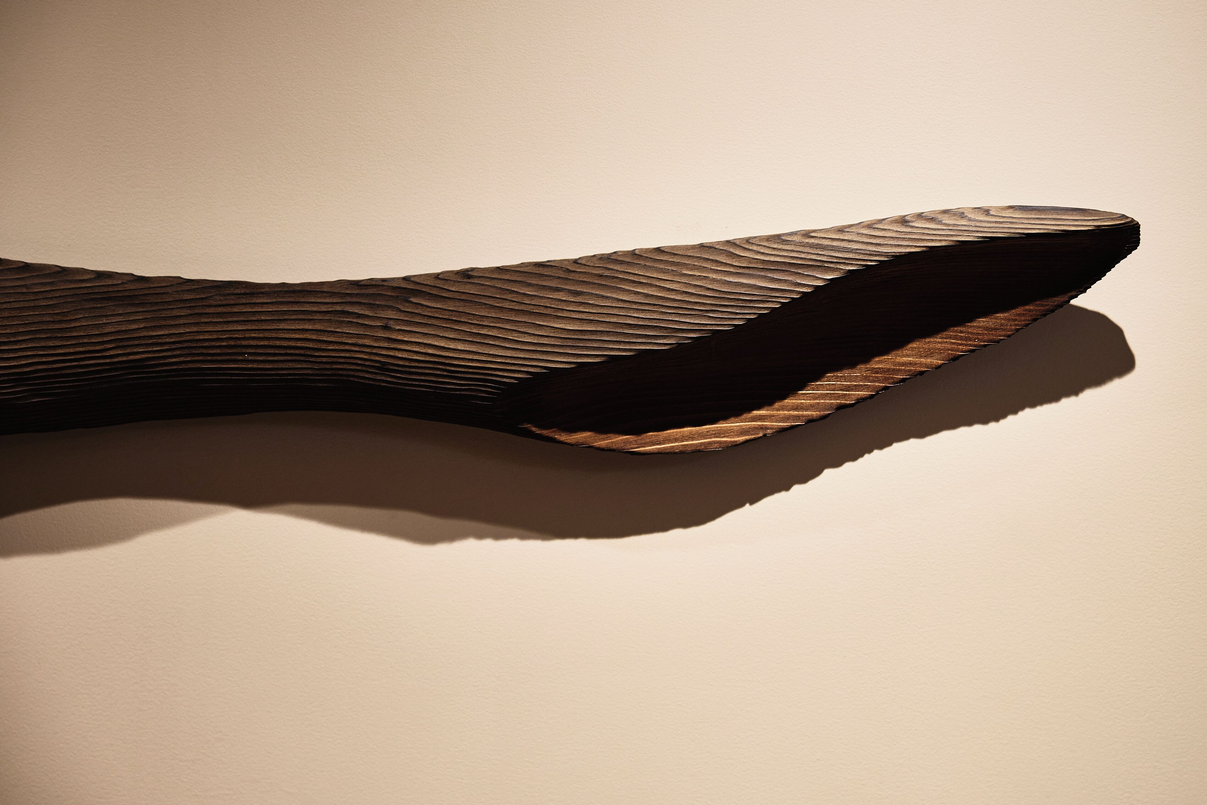 Une sculpture en bois à la surface texturée et aux formes courbes.