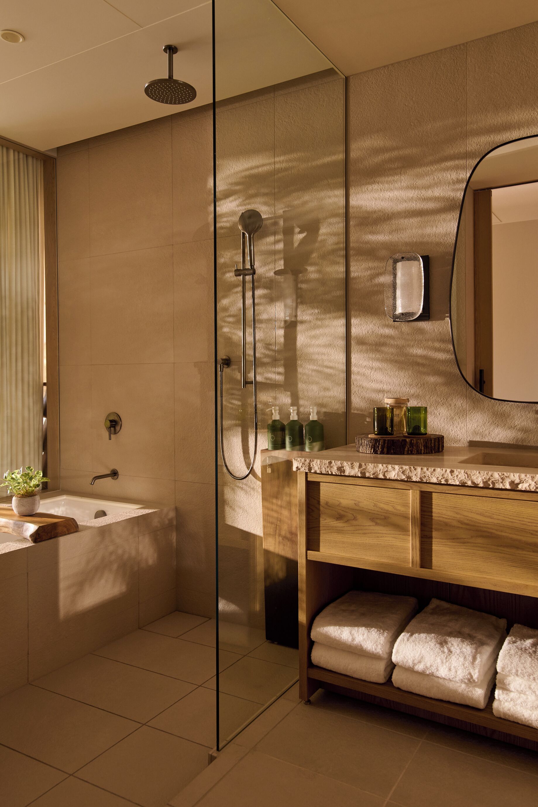 A modern bathroom with a glass-enclosed shower, a wooden vanity, and a large mirror.